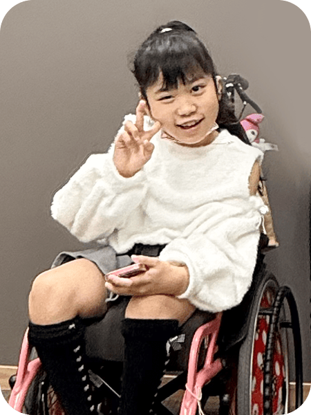 車椅子に乗ってにっこりピースしている女の子