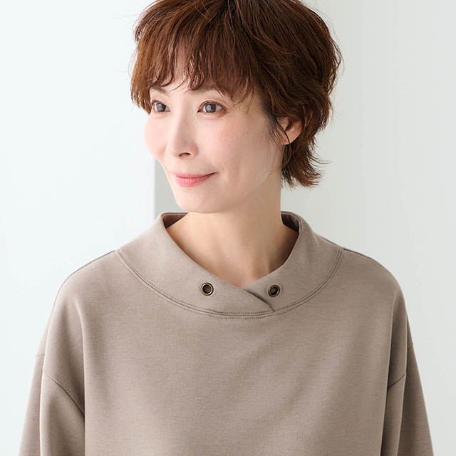 フード見えするスタンドネックとアンティークゴールド調のアイレットがさりげなく上品