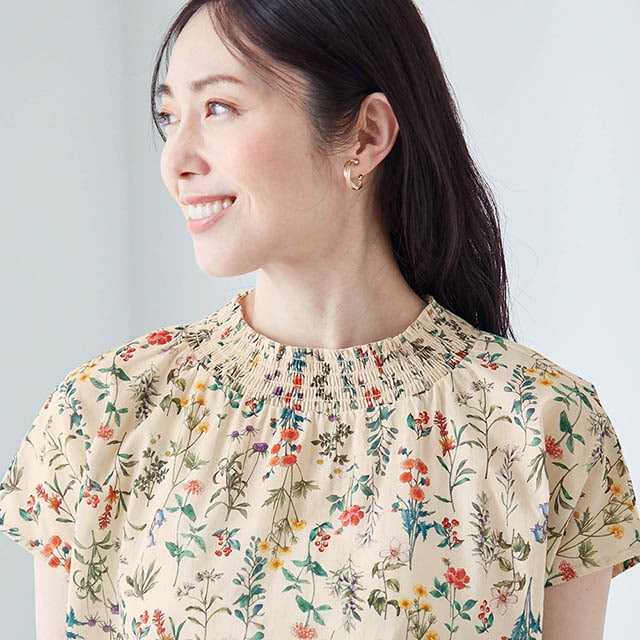 やや高めの襟が首まわりをカバーし、シャーリングで華やぎを演出