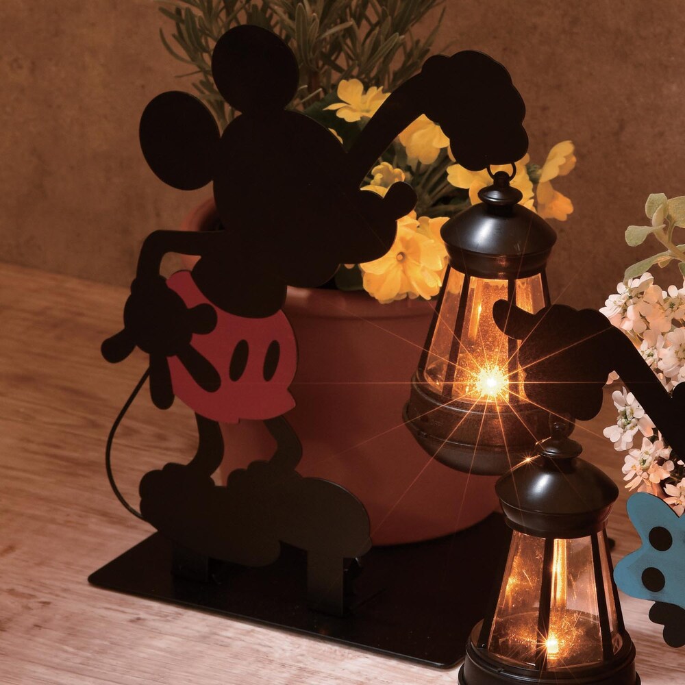 ランプを持ったディズニーキャラクターを、シルエットで表現したソーラーライト昼間、太陽の光を浴びて充電するので電気代ゼロろうそくの灯りのように光がゆらぐLEDが、庭先を素敵に演出