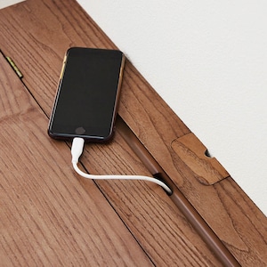 溝にはスマートフォンを立て掛けたまま充電できるコード穴、奥にももう1つコード穴があり、機能が充実。