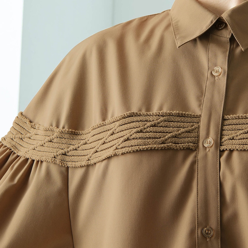 胸元にケーブル編みのニットをあしらった目を引くデザイン