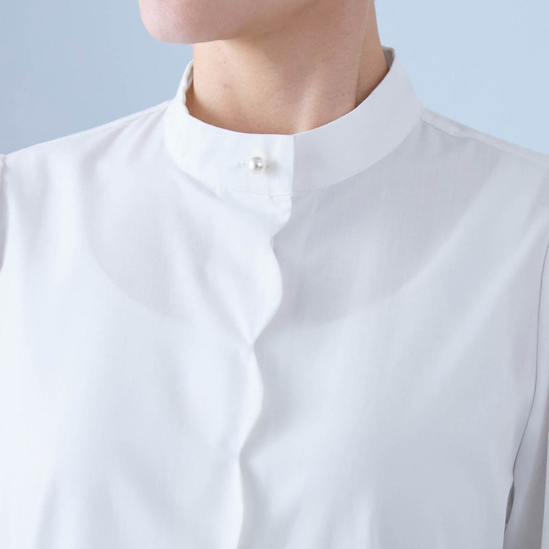 スタンドネックにパール調のボタンがアクセント