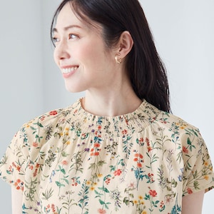 やや高めの襟が首まわりをカバーし、シャーリングで華やぎを演出