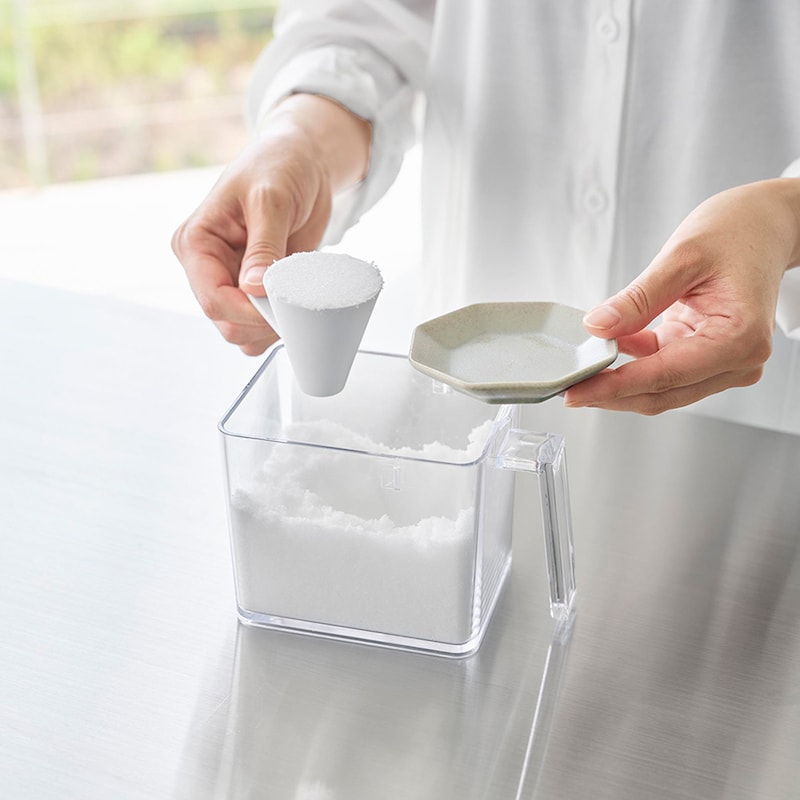 スプーンのハンドル部分を容器の縁でかるくたたき、粗塩をなじませながら先端まで行き渡らせます